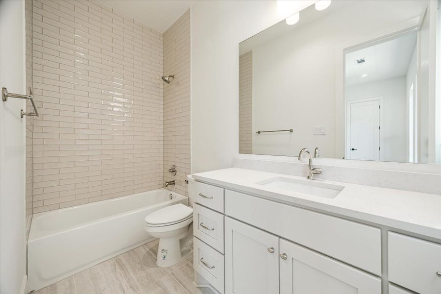 En-suite bath - has shower/tub combo and quartz countertop.