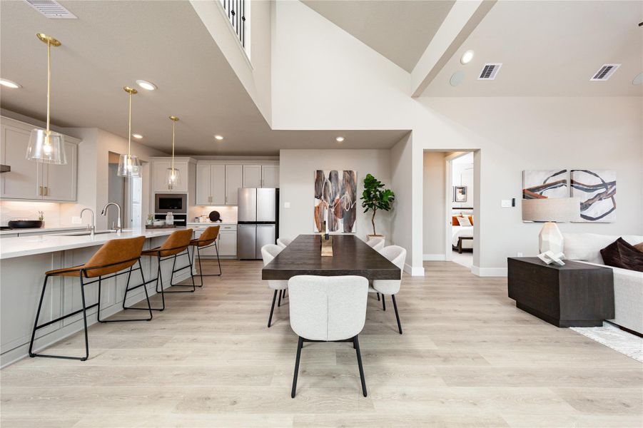 This bright dining space seamlessly connects the main living areas, making it ideal for seamless entertaining and everyday living. Anchored by soaring vaulted ceilings, the open-concept layout effortlessly bridges the gourmet kitchen and the adjacent great room. Durable, wide-plank flooring flows throughout the entire main level, while recess lighting and an abundance of natural light from the open floor plan create a warm, inviting ambiance.
