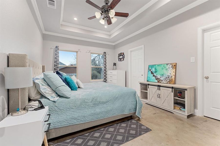 Bedroom with ceiling fan, ornamental molding, and a tray ceiling