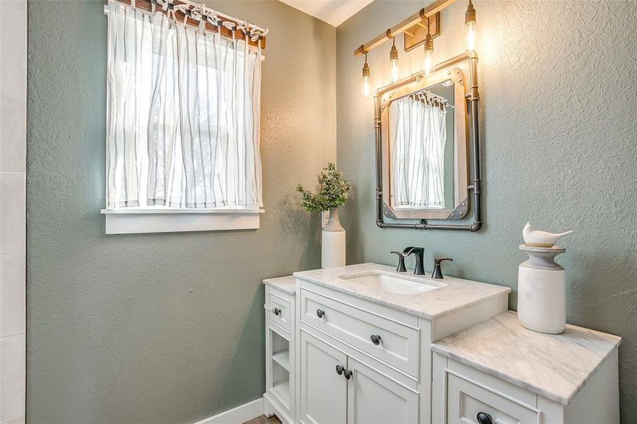 Bathroom featuring a textured wall and vanity