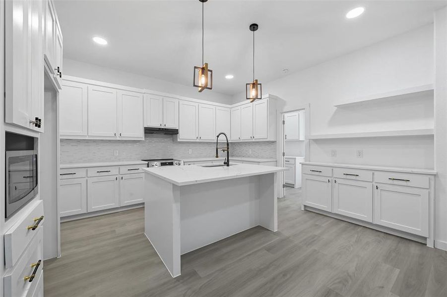 Kitchen with decorative backsplash, decorative light fixtures, white cabinetry, and recessed lighting Kitchen with decorative backsplash, decorative light fixtures, white cabinetry, and recessed lighting