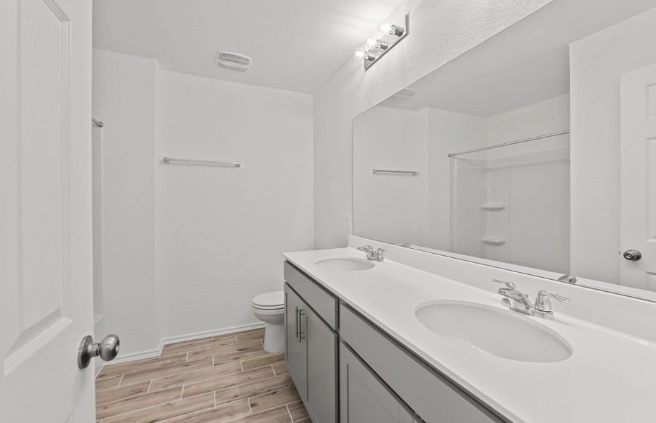 Full bathroom with wood tiled floors and double vanity Full bathroom with wood tiled floors and double vanity
