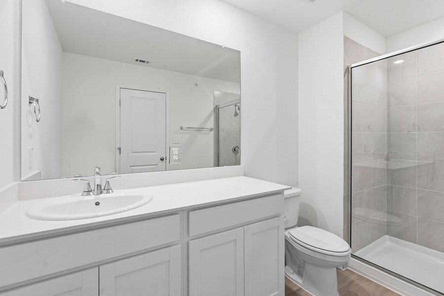 Bathroom featuring a white vanity with an integrated sink, polished chrome faucet, a large frameless mirror, and a glass-enclosed shower with tiled walls and a white shower pan Bathroom featuring a white vanity with an integrated sink, polished chrome faucet, a large frameless mirror, and a glass-enclosed shower with tiled walls and a white shower pan