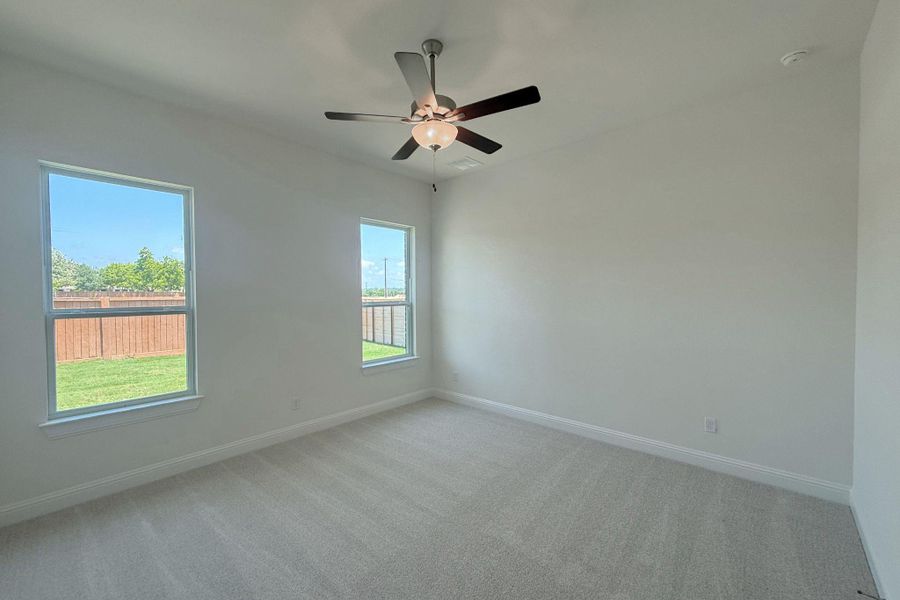 Bright interior space featuring light-colored carpeting, two windows, painted walls, and a ceiling fan with integrated lighting