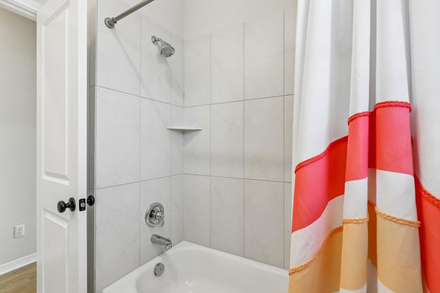 A pristine tiled shower with a bathtub, offering a refreshing and clean bathing experience.