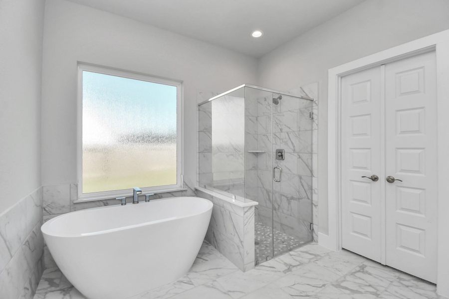 Indulge in a spa-like retreat within the confines of this primary bathroom. Delight in a spacious walk-in shower enveloped in stylish tile surround and unwind in a separate garden tub adorned with custom detailing. Sample photo of completed home with similar floor plan. Actual colors and selections may vary.