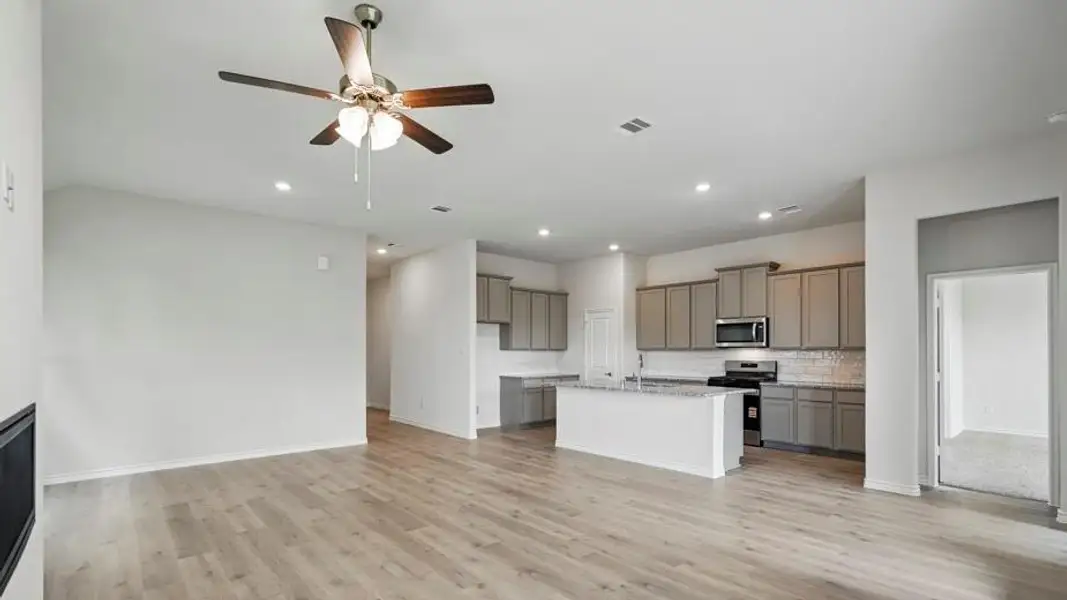 Kitchen with ceiling fan, stainless steel appliances, gray cabinets, a kitchen island with sink, and light stone countertops