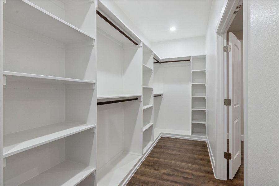 Discover the luxury of a spacious walk-in primary closet, offering abundant shelving and elegant design for your wardrobe needs.