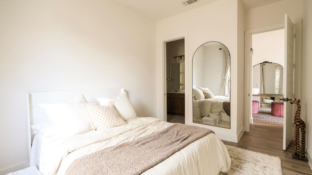 A well-lit bedroom offering direct access to both a private bathroom and an adjacent dressing area. A well-lit bedroom offering direct access to both a private bathroom and an adjacent dressing area.