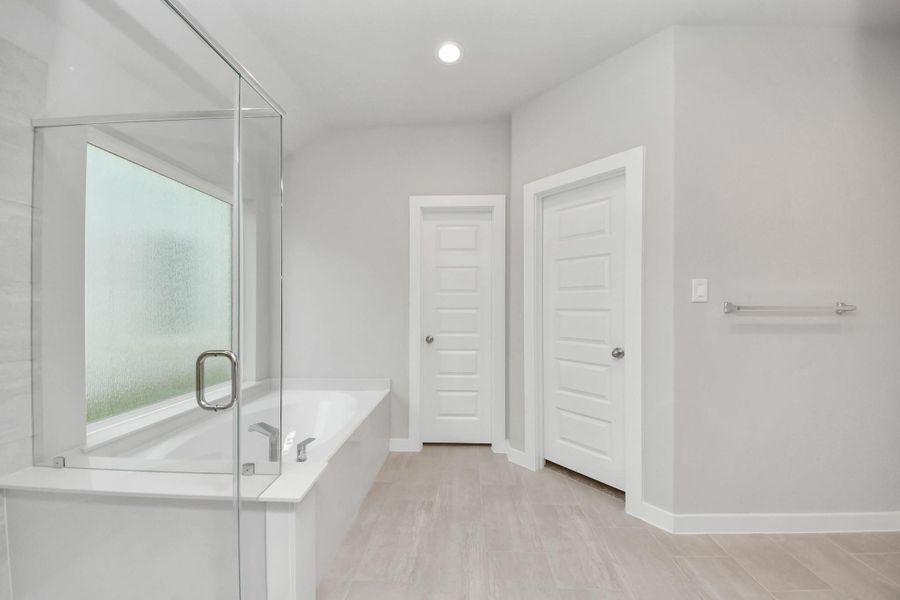 Indulge in a spa-like retreat within the confines of this primary bathroom. Delight in a spacious walk-in shower enveloped in stylish tile surround, unwind in a separate garden tub adorned with custom detailing.