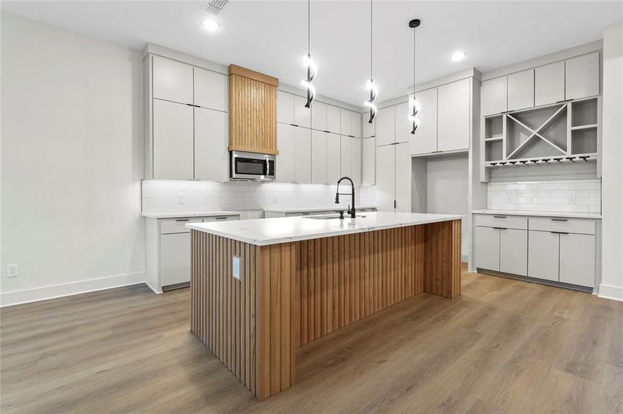Kitchen with brown cabinetry, white cabinets, modern cabinets, and light wood-style flooring