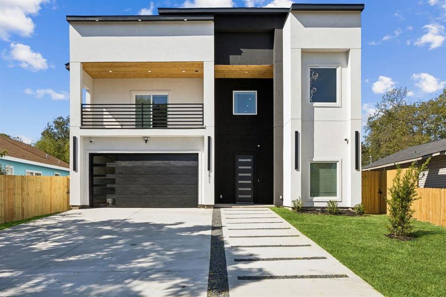 Contemporary house featuring stucco siding, a balcony, concrete driveway, and a garage