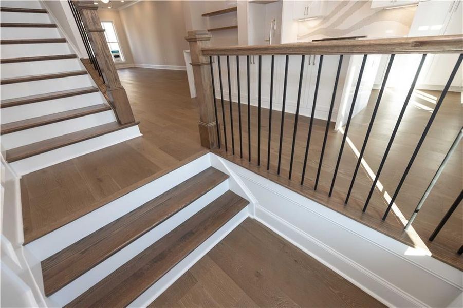 Staircase featuring wood finished floors and open rails throughout.  Image is of a previously built Chamberlain plan