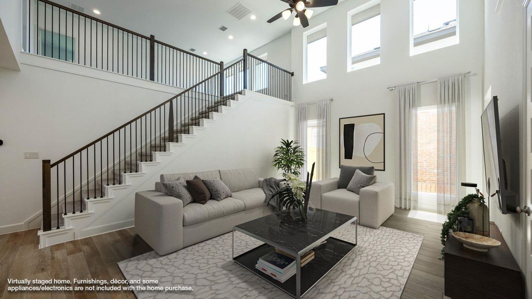 Living room with wood finished floors, a high ceiling, stairway, plenty of natural light, and ceiling fan Living room with wood finished floors, a high ceiling, stairway, plenty of natural light, and ceiling fan