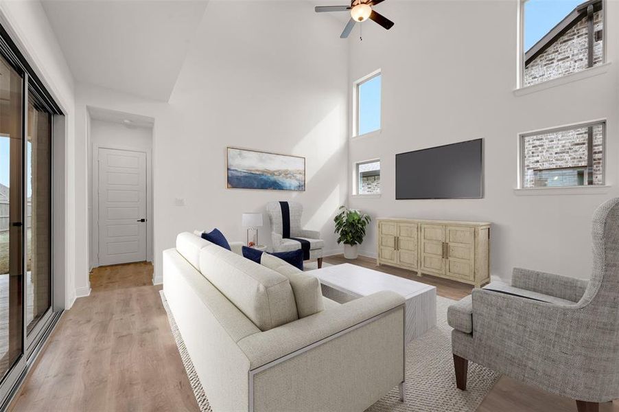 Living room featuring a high ceiling, light wood finished floors, and ceiling fan