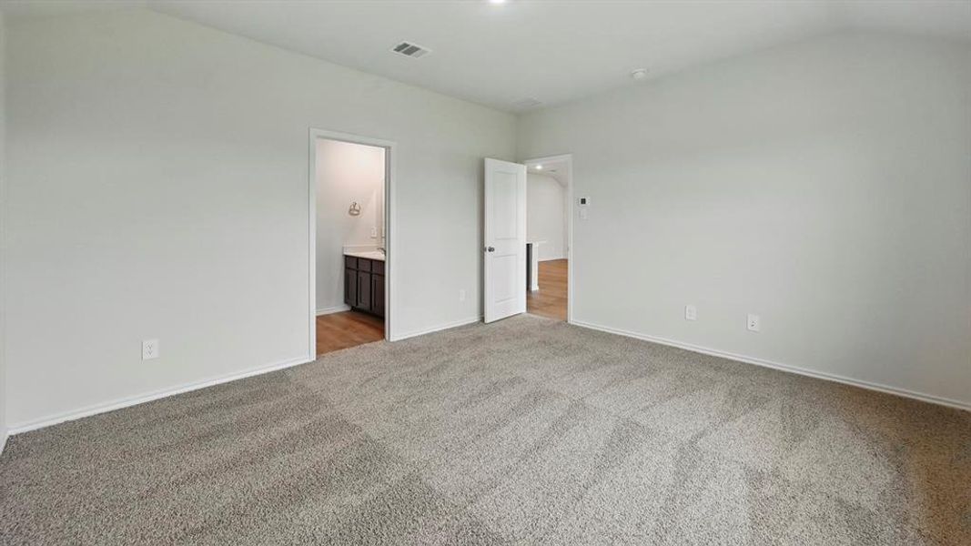 Unfurnished bedroom with carpet floors, connected bathroom, and vaulted ceiling