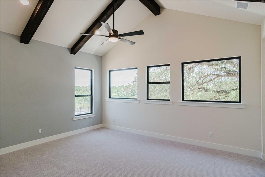 Unfurnished room featuring ceiling fan, light carpet, healthy amount of natural light, beamed ceiling, and high vaulted ceiling