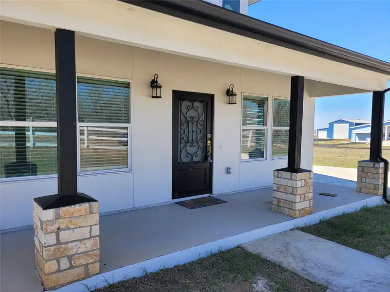 Entrance to property with covered porch and stucco siding