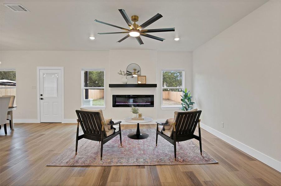 Living area with a healthy amount of sunlight, ceiling fan, and light wood-type flooring