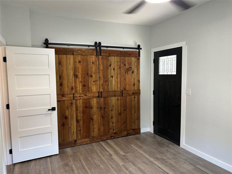 Foyer entrance with wood finished floors, a barn door, and a ceiling fan Foyer entrance with wood finished floors, a barn door, and a ceiling fan