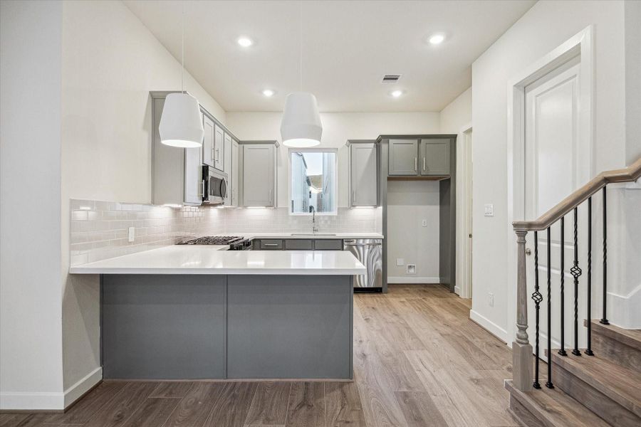 Open kitchen with large peninsula, quartz counters, and ample cabinetry.