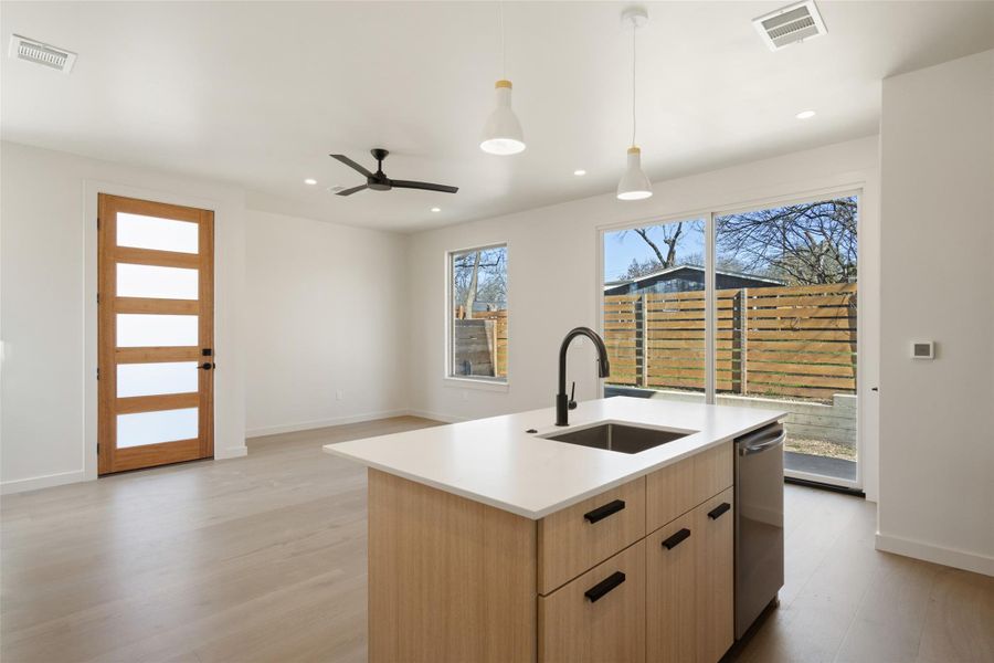 Kitchen with light brown cabinets, stainless steel dishwasher, a sink, and visible vents