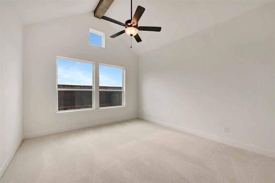 Spacious room featuring vaulted ceilings with an exposed beam, a ceiling fan with integrated lighting, and carpet flooring