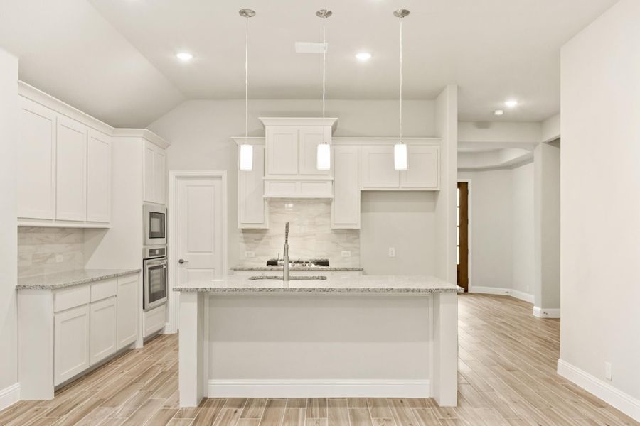 White kitchen with center island, granite countertops, pendant lights, and stainless steel double oven White kitchen with center island, granite countertops, pendant lights, and stainless steel double oven