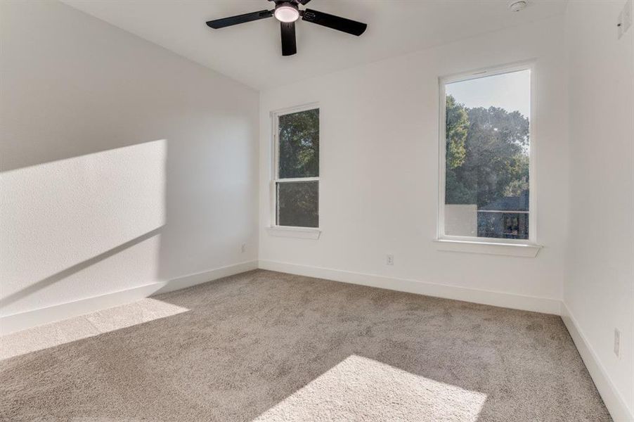 Empty room with light carpet and a ceiling fan Empty room with light carpet and a ceiling fan