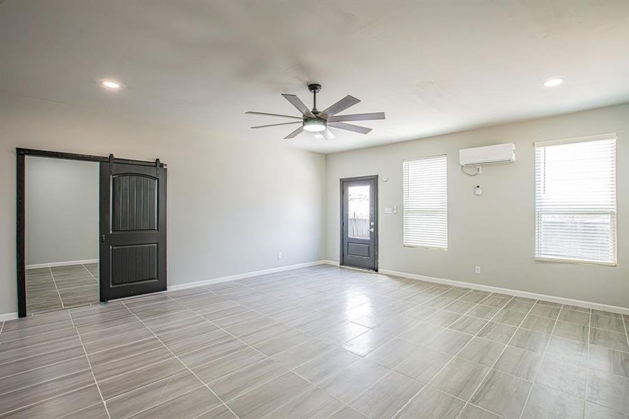 Empty room with baseboards, a wall mounted AC, recessed lighting, ceiling fan, and a barn door