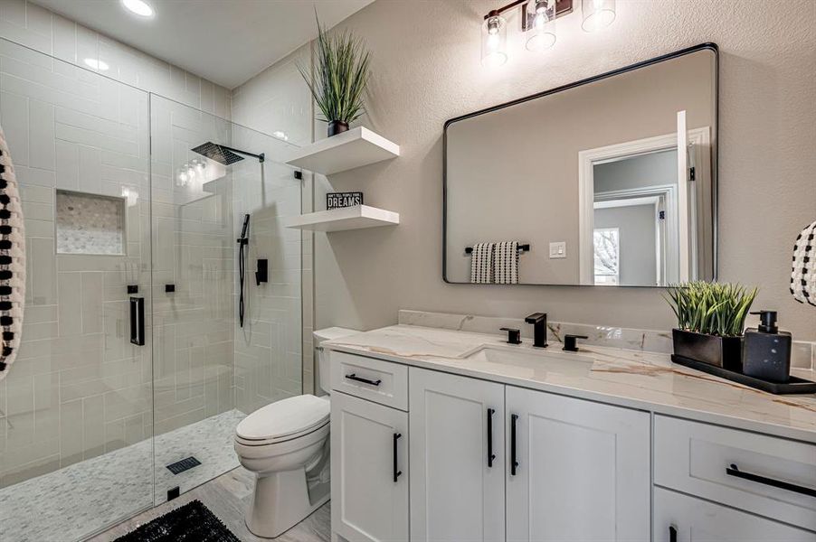 Bathroom featuring vanity, toilet, and a shower with door