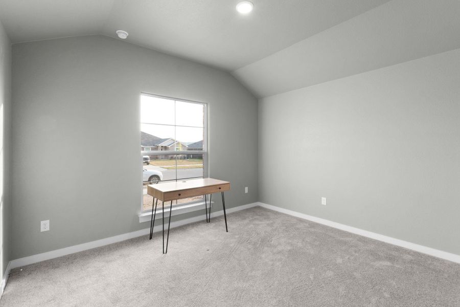 A well-lit bedroom features vaulted ceilings and soft carpet, providing a comfortable retreat.