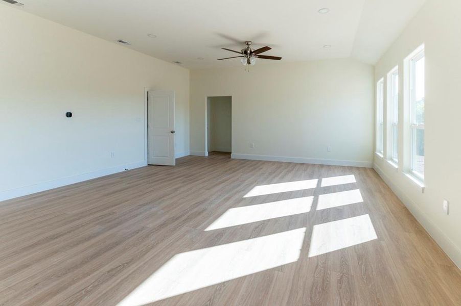 Spare room featuring light wood-style floors, vaulted ceiling, and ceiling fan