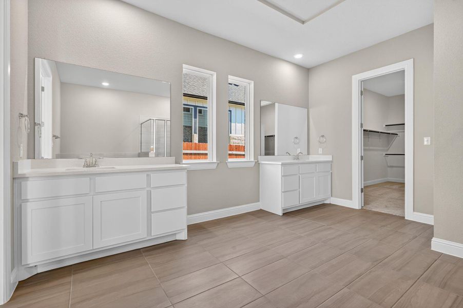 Full bath featuring two vanities, a stall shower, recessed lighting, a spacious closet, and light tile patterned floors