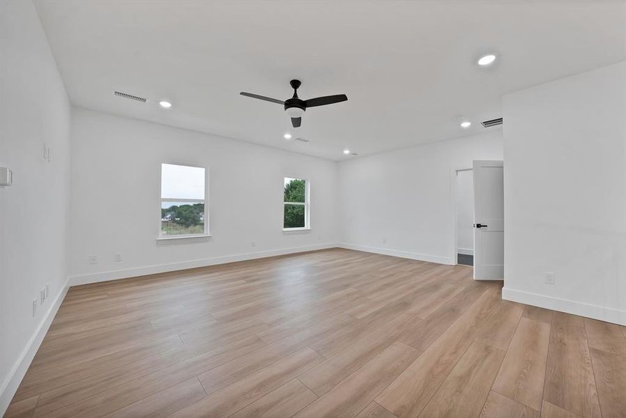 Spacious room featuring wood-finish flooring, a modern black ceiling fan, recessed lighting, and white baseboards