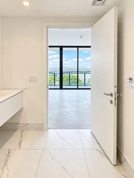 Large-format tile flooring with marble-style veining, floating vanity cabinet, and expansive floor-to-ceiling glass sliding doors with black framing Large-format tile flooring with marble-style veining, floating vanity cabinet, and expansive floor-to-ceiling glass sliding doors with black framing