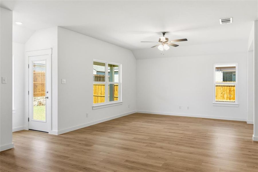 Spare room featuring vaulted ceiling, ceiling fan, and light wood-type flooring