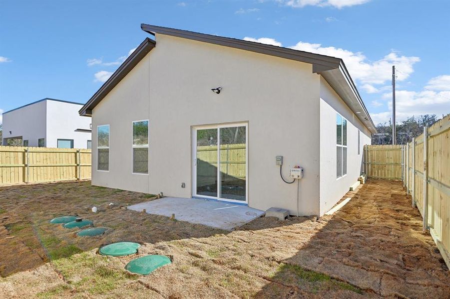 Rear view of house with stucco siding, a fenced backyard, and a patio