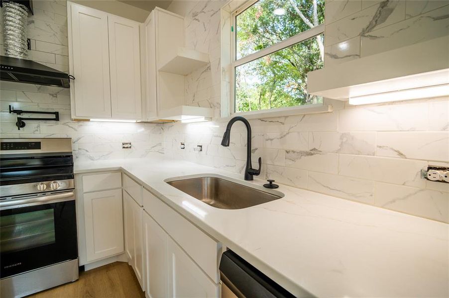 Kitchen featuring white cabinetry, stainless steel range, sink, and decorative backsplash