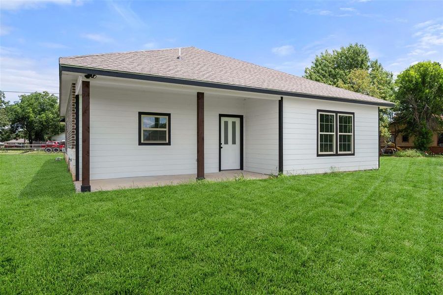 Rear view of property featuring roof with shingles and a yard Rear view of property featuring roof with shingles and a yard