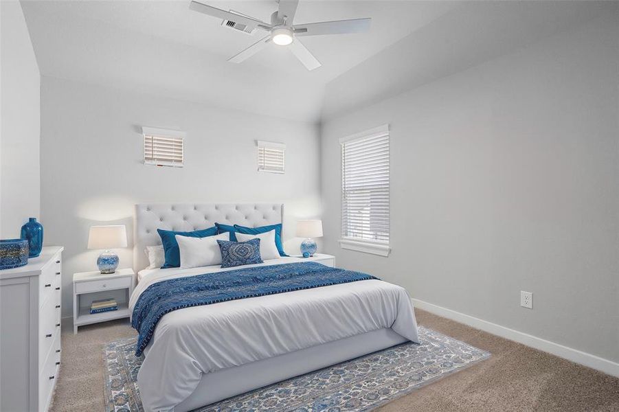 Secondary bedroom features plush carpet, custom paint, ceiling fan with lighting and a large window with privacy blinds.