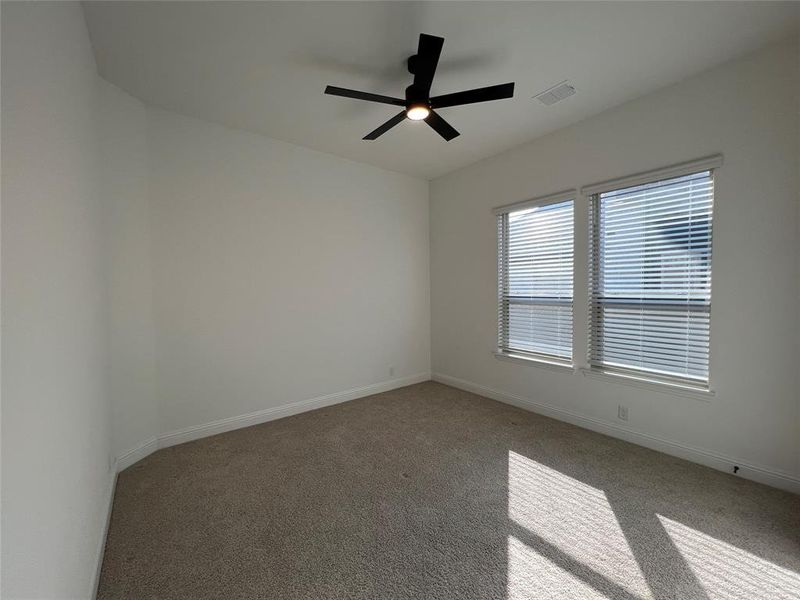 Guest bedroom featuring ceiling fan, walk-in closet, and carpet flooring Guest bedroom featuring ceiling fan, walk-in closet, and carpet flooring