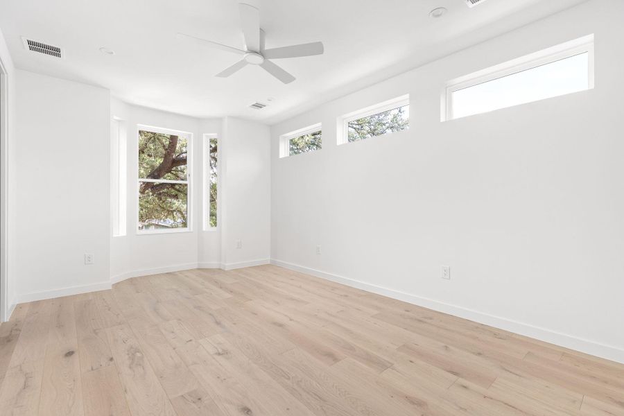 Empty room with plenty of natural light, light wood-style flooring, and ceiling fan Empty room with plenty of natural light, light wood-style flooring, and ceiling fan