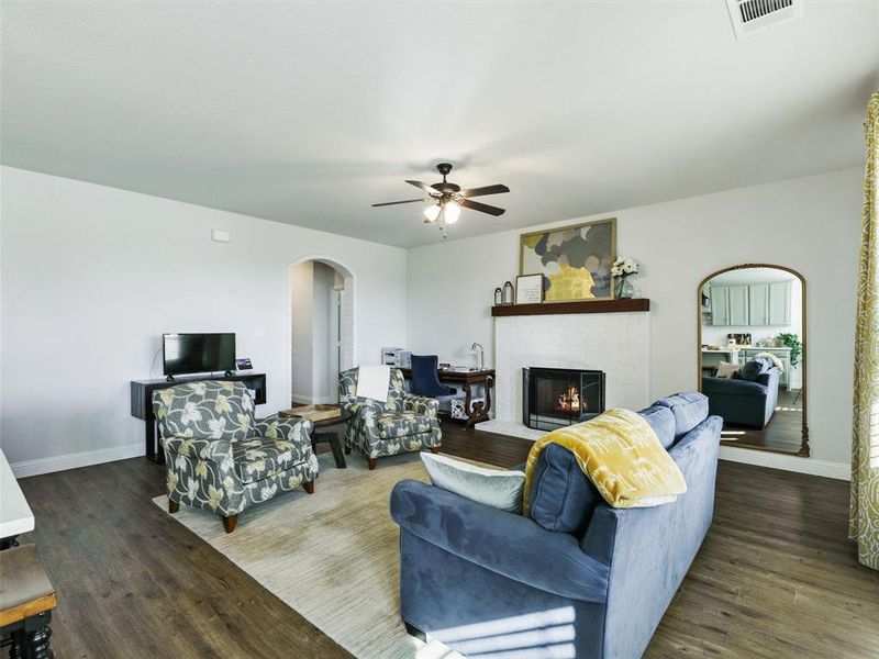 Living room featuring ceiling fan, dark hardwood / wood-style flooring, and a fireplace