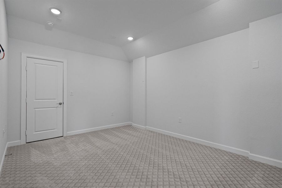 Unfurnished room with light colored carpet and lofted ceiling Unfurnished room with light colored carpet and lofted ceiling