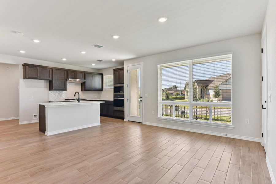 Kitchen featuring plenty of natural light, recessed lighting, dark brown cabinets, and a kitchen island with sink