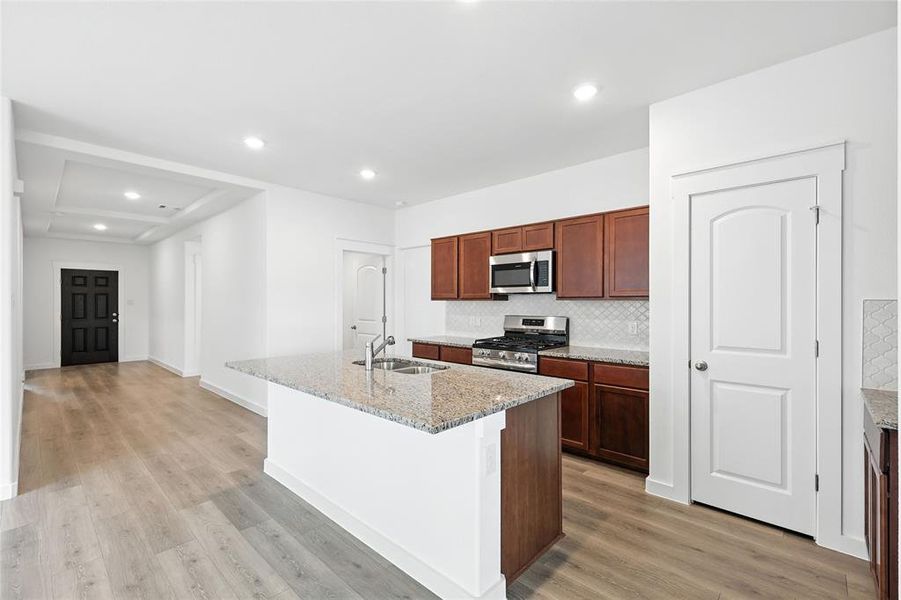 Kitchen with tasteful backsplash, recessed lighting, a center island with sink, light stone counters, and appliances with stainless steel finishes Kitchen with tasteful backsplash, recessed lighting, a center island with sink, light stone counters, and appliances with stainless steel finishes