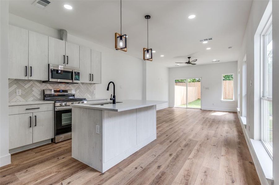 Kitchen with stainless steel Samsung appliances, backsplash, a sink, visible vents, and open floor plan