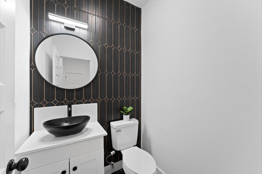 A lovely half bath features a vessel sink, stylish mirror and a fantastic accent wall.