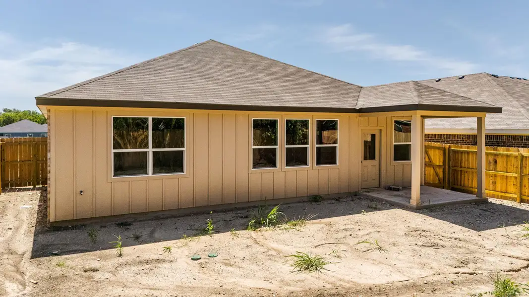 Back of property with roof with shingles and a patio area
